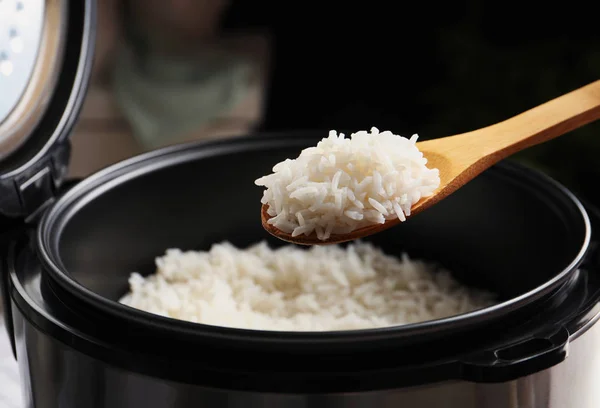 Ложка зі смачним гарячим рисом над плитою, крупним планом — стокове фото