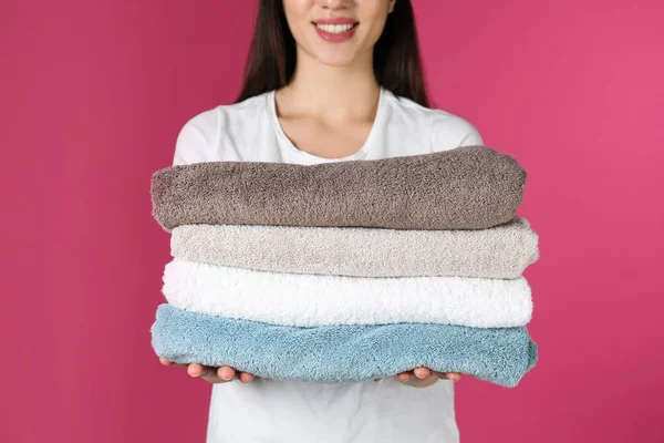 Young woman holding clean towels on color background, closeup. Laundry day — Stock Photo, Image