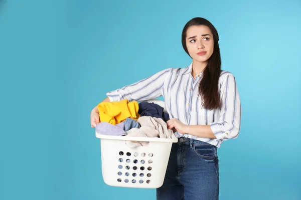 Hoşnutsuz genç kadın renkli arka plan üzerinde çamaşır sepeti tutan — Stok fotoğraf