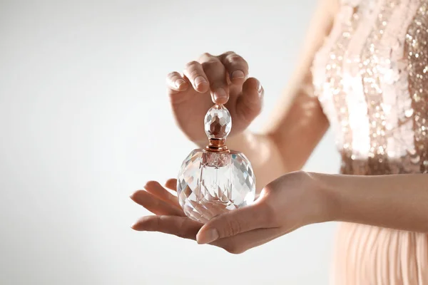 Mujer joven con botella de perfume sobre fondo claro, primer plano. Espacio para texto — Foto de Stock