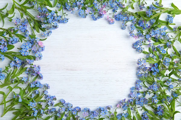 Frame gemaakt van verbazingwekkende lente Forget-me-not bloemen op witte houten achtergrond, platte lag. Ruimte voor tekst — Stockfoto