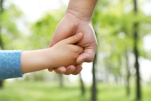 Litet barn håller händerna med sin far utomhus, närbild. Familjens tid — Stockfoto