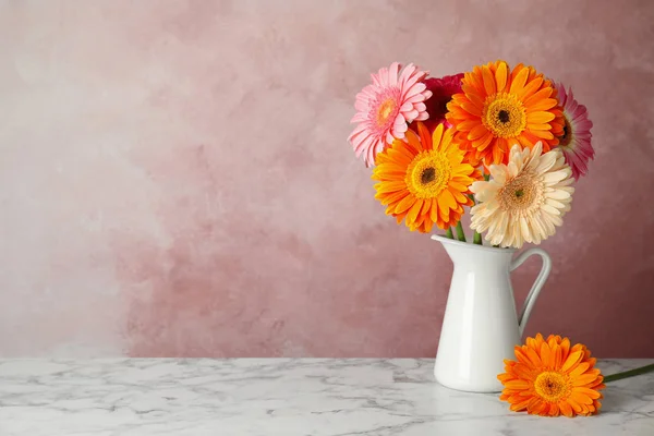 Букет красивых ярких цветов герберы в вазе на мраморном столе на цветном фоне — стоковое фото
