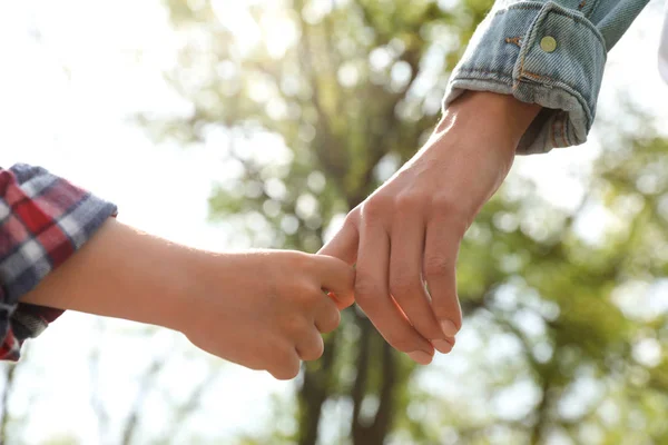 Niño pequeño cogido de la mano con su madre al aire libre, de cerca. Tiempo en familia —  Fotos de Stock