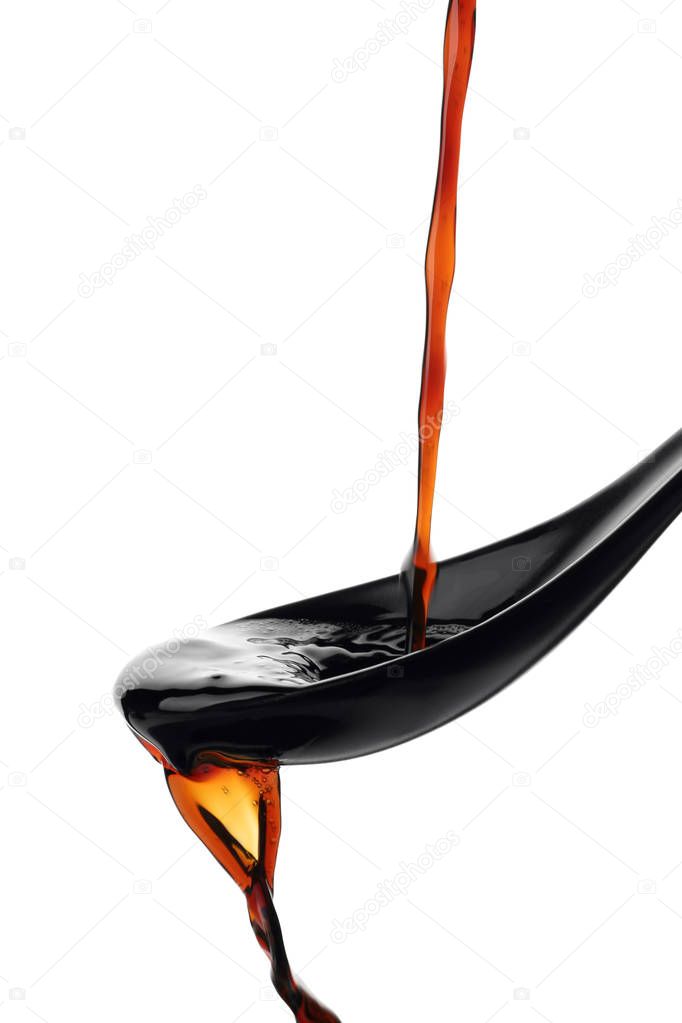 Pouring soy sauce into spoon against white background