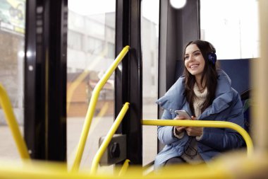Genç kadın toplu taşıma kulaklıklar ile müzik dinleme