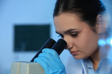 Kimya laboratuvarında mikroskop kullanan kadın bilim adamı, metin için alan