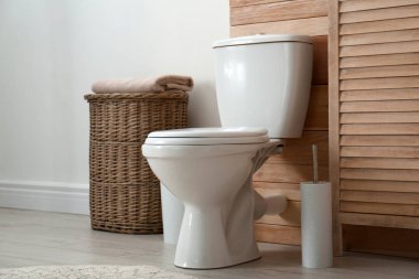 Toilet bowl near wooden wall in modern bathroom interior clipart
