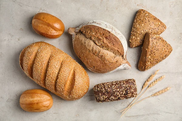 Różne rodzaje świeżego chleba na szarym stole, płaskie leżaki — Zdjęcie stockowe