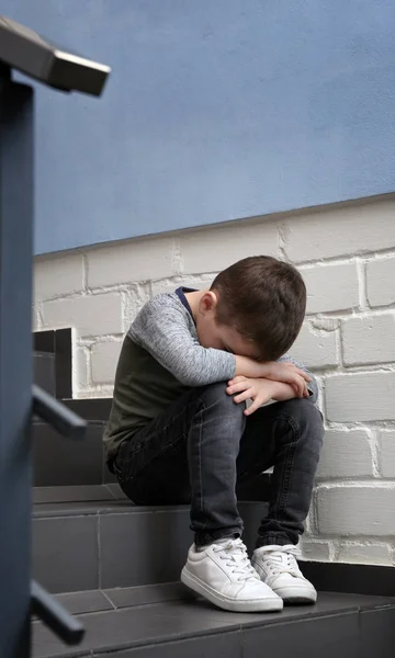Kapalı merdivenlerde oturan üzücü küçük çocuk — Stok fotoğraf