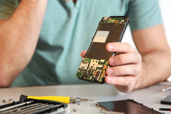 Técnico con teléfono móvil en la mesa en taller de reparación, primer plano —  Fotos de Stock