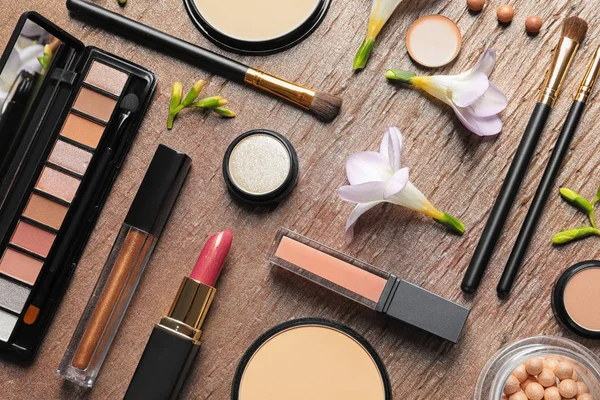 Många olika makeup produkter och vårblommor på färg bakgrund, uppifrån — Stockfoto