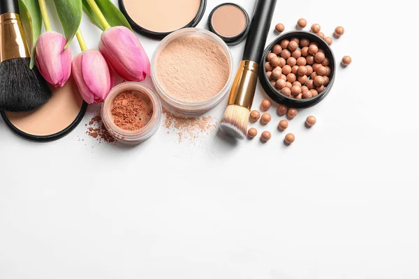 Många olika makeup produkter och vårblommor på vit bakgrund, uppifrån — Stockfoto