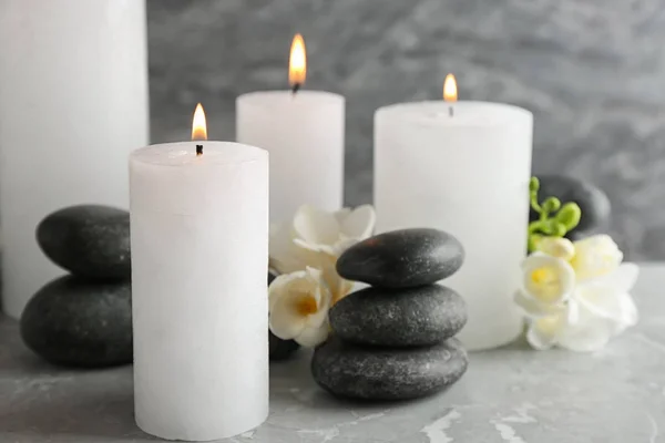 Burning candles, spa stones and flowers on table. Space for text — Stock Photo, Image