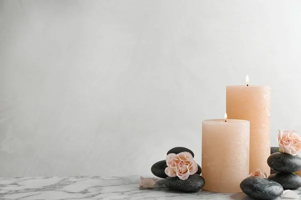 Склад палаючих свічок, спа-кам'яних і квітів на столі. Простір для тексту — стокове фото
