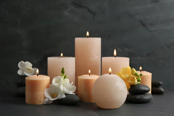 Složení hořících svíček, lázeňských kamenů a květin na stole — Stock fotografie