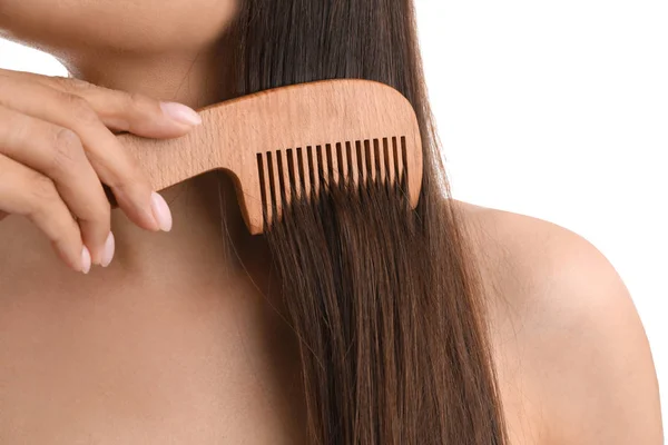 Jovem mulher com pente de cabelo de madeira no fundo branco, close-up — Fotografia de Stock