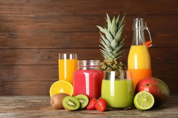 Artículos de vidrio con diferentes jugos y frutas frescas sobre fondo de madera. Espacio para texto — Foto de Stock