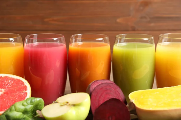 Glas med olika juicer och färska ingredienser på trä bakgrund — Stockfoto
