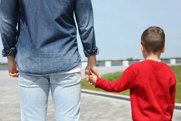 Bambino che si tiene per mano con suo padre all'aperto. Weekend in famiglia — Foto Stock