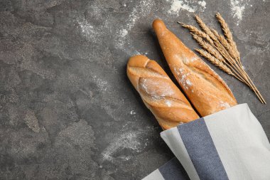 Gri arka plan üzerinde metin için peçete ve boşluk sarılmış bagetler ile düz yatıyordu kompozisyon. Taze ekmek