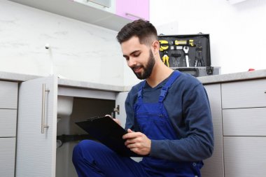 Mutfak lavabosu yakınında pano ile erkek tesisatçı. Onarım hizmeti