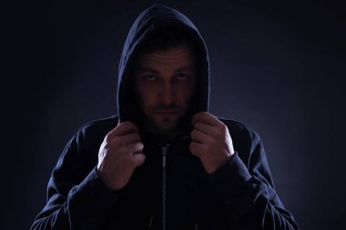 Karanlık arka planda kapüşonlu gizemli adam. Tehlikeli suçlu