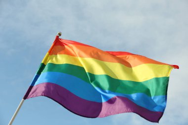 Parlak gökkuşağı gay bayrağı mavi gökyüzüne karşı çırpınan. Lgbt topluluğu