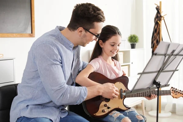 Dziewczynka gra na gitarze z nauczycielem na lekcji muzyki. Notatki edukacyjne — Zdjęcie stockowe