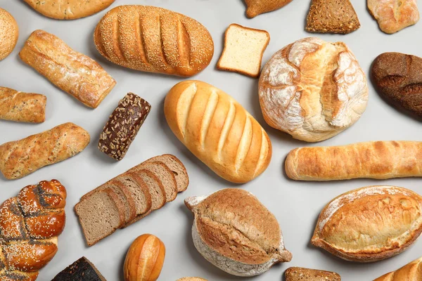 Diferentes tipos de pan fresco sobre fondo claro, plano laico — Foto de Stock
