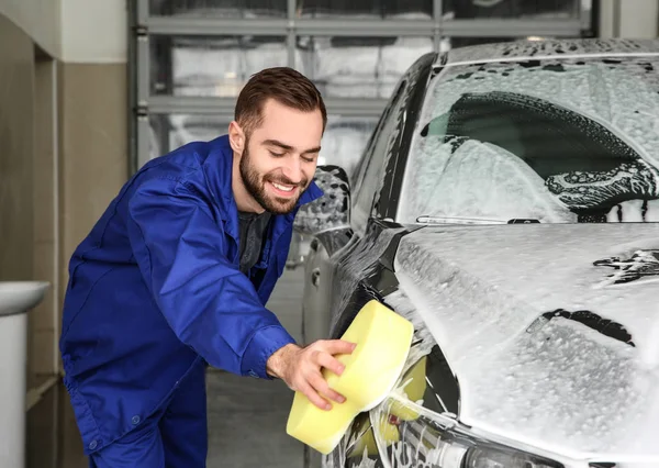 Trabalhador de limpeza automóvel com esponja em lavagem de carro profissional — Fotografia de Stock