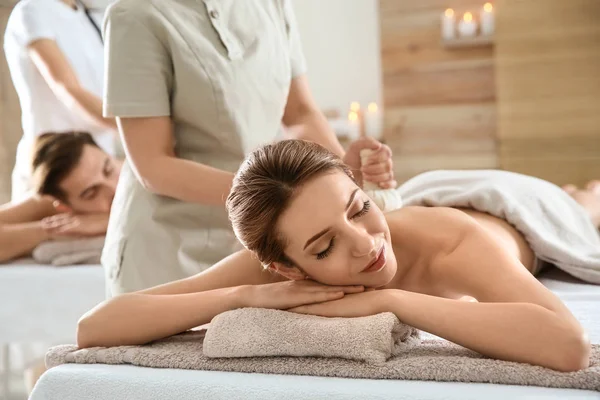 Romântico jovem casal desfrutando de massagem saco de ervas no salão de spa — Fotografia de Stock