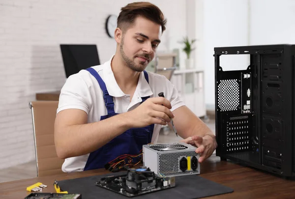 Male technician repairing power supply unit at table indoors — Stock Photo, Image