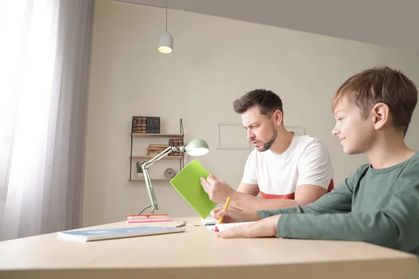 Papa luttant pour aider son fils avec l'affectation scolaire à la maison — Photo