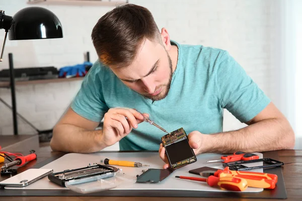 Technicien réparer téléphone portable à table dans l'atelier — Photo