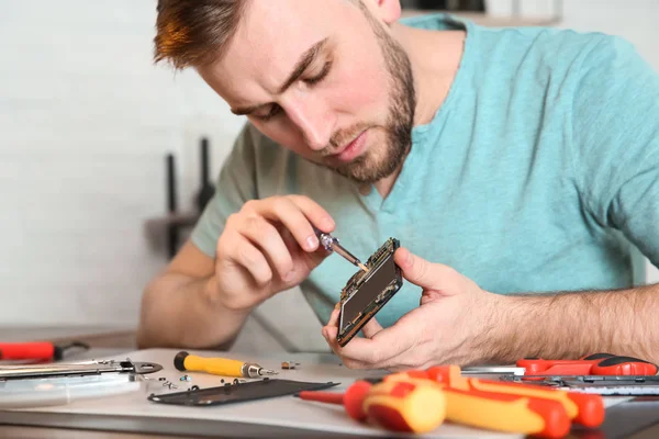 Technicien réparer téléphone portable à table dans l'atelier, gros plan — Photo