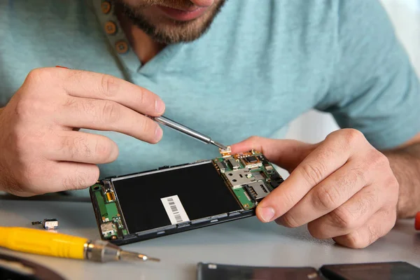 Technicien réparer téléphone portable à table, gros plan — Photo