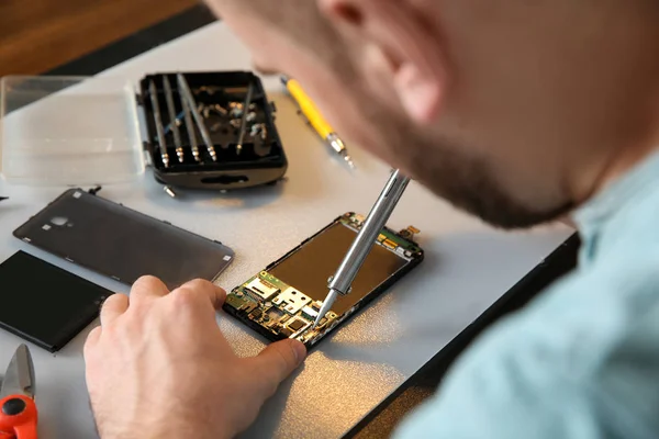 Technicien réparer téléphone portable à table, gros plan — Photo
