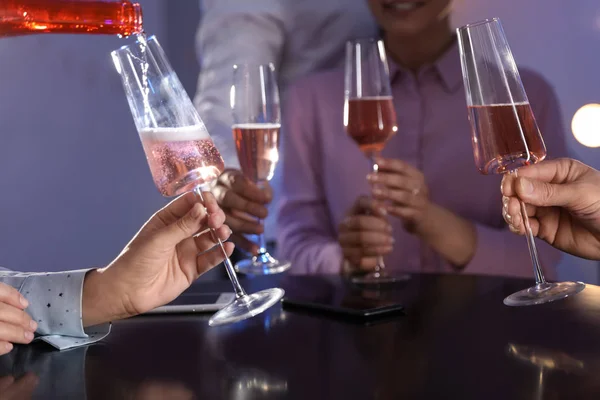 Donna che riempie il bicchiere di champagne e le sue amiche a tavola nel bar, primo piano — Foto Stock