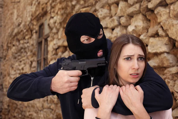 Maskierter Mann mit Waffe hält Frau im Freien als Geisel Straftat — Stockfoto