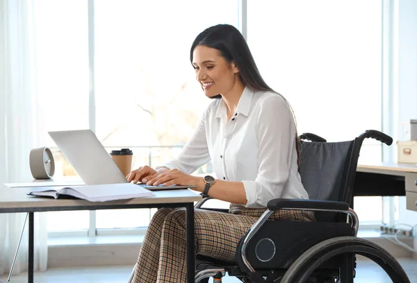 Młoda kobieta na wózku inwalidzkim przy użyciu laptopa w miejscu pracy — Zdjęcie stockowe