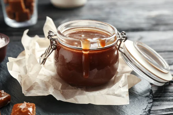 Pot avec sauce caramel savoureuse sur la table — Photo