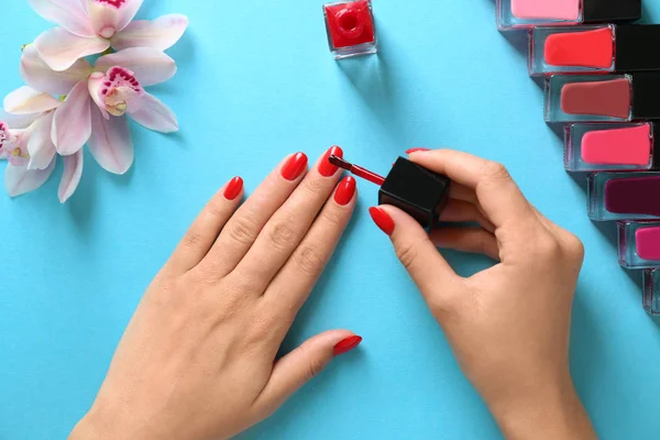 Woman applying bright nail polish on color background, top view — Stock Photo, Image