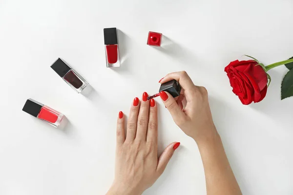 Mujer aplicando esmalte de uñas brillante sobre fondo blanco, vista superior — Foto de Stock