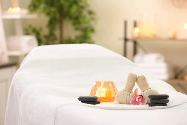 Composição com sacos de ervas, vela e pedras na mesa de massagem no salão de spa — Fotografia de Stock