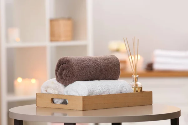 Bandeja com toalhas e purificador de ar de junco na mesa no salão de spa — Fotografia de Stock