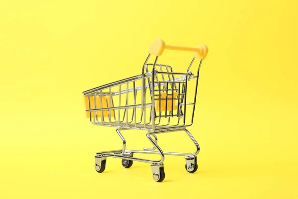 Prázdný nákupní vozík s rukojetí na barevném pozadí — Stock fotografie