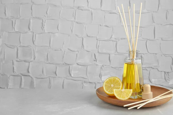 Placa com ambientador de palhetas aromático e limão na mesa contra parede texturizada. Espaço para texto — Fotografia de Stock