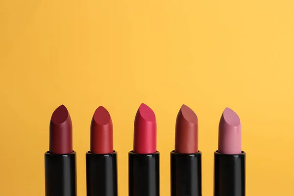 Diferentes lápices labiales sobre fondo de color. Maquillaje producto cosmético — Foto de Stock