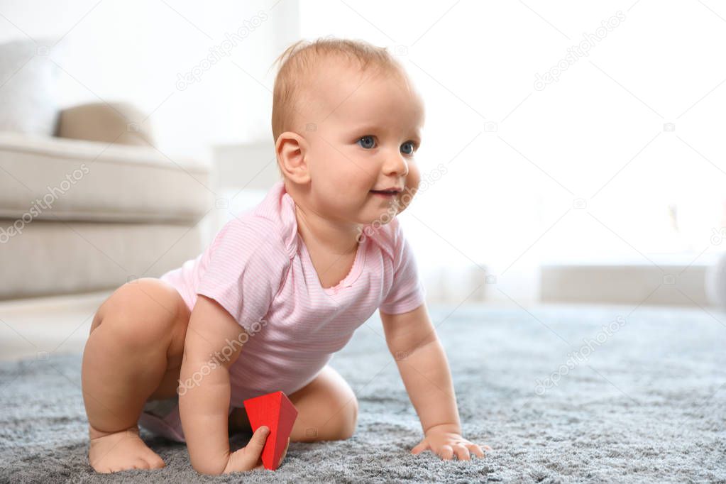 Cute baby girl playing on floor in room. Space for text